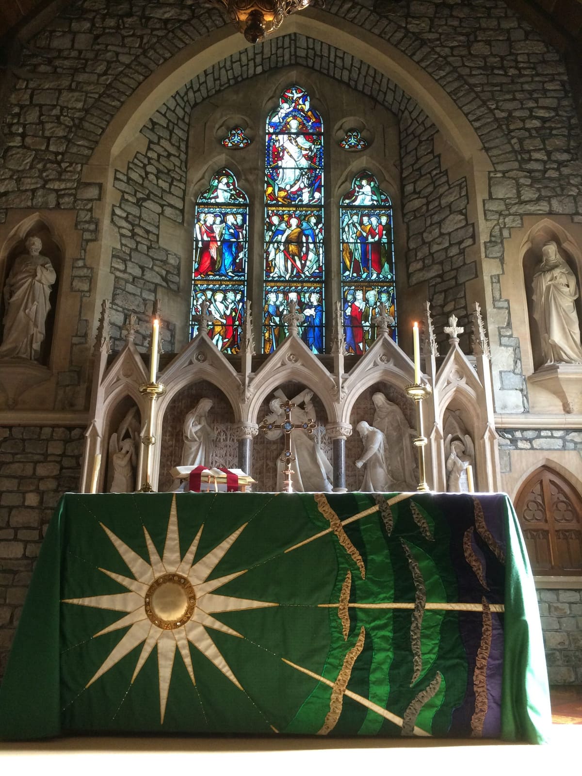 The altar at St Peter's with its green embroidered frontal and stained glass